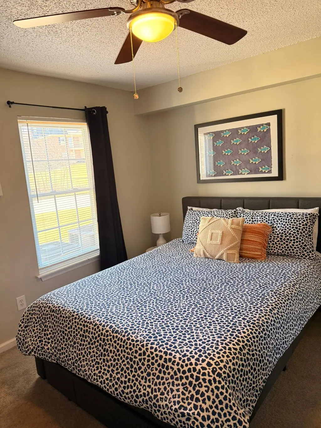Rental bedroom with a freshly made bed, accent pillows and a ceiling fan, ready for the next guest