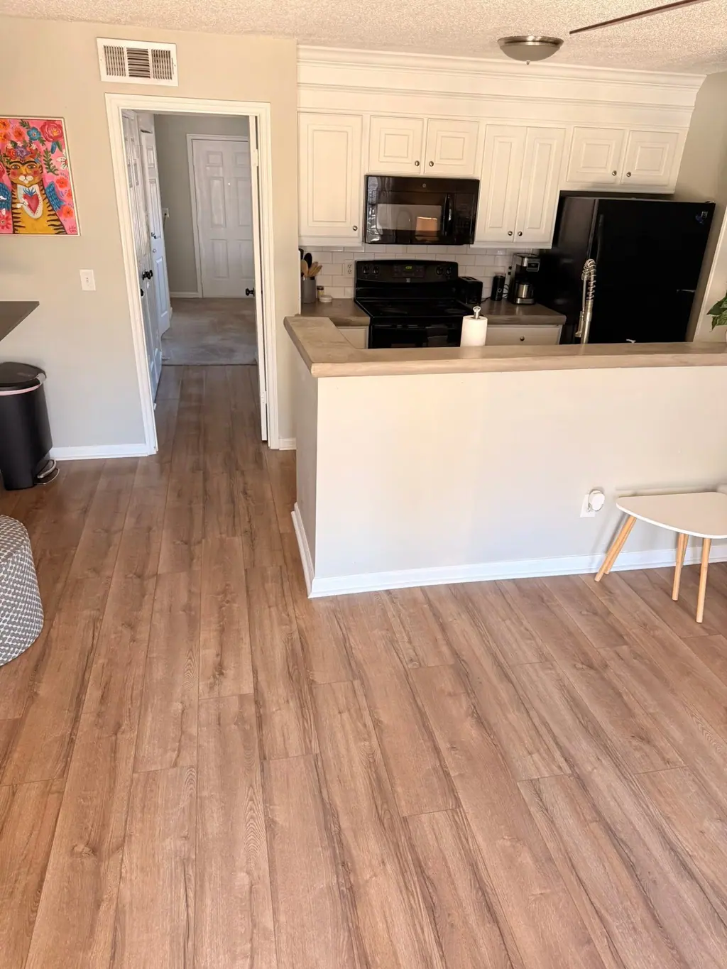 Open apartment kitchen and living area with wood-look floors after a turnover clean