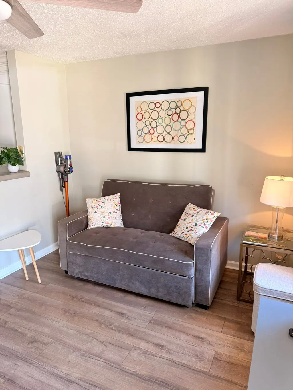 Rental living room with a gray loveseat, side tables and wood-look floors after a turnover