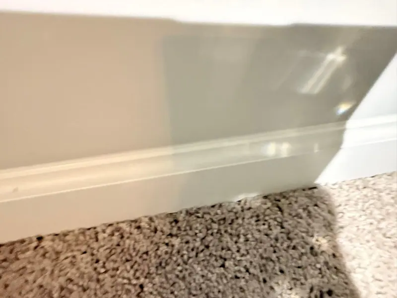 White baseboard wiped clean above freshly vacuumed carpet