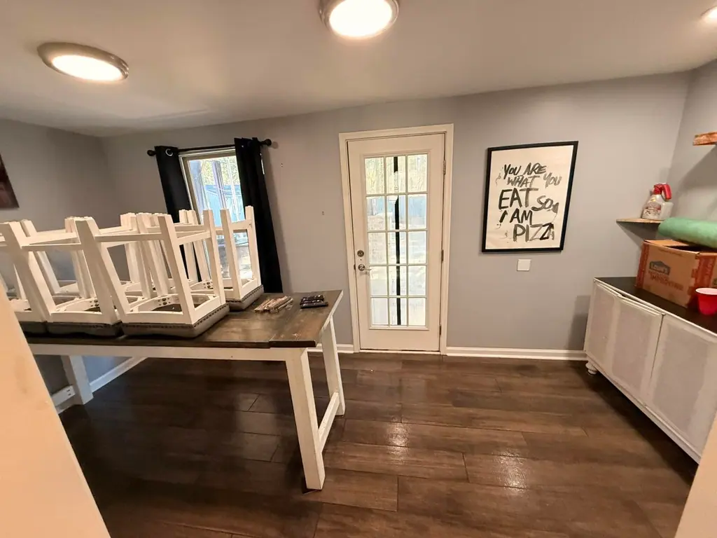 Dining room with the chairs up on the table while the dark wood floor is cleaned