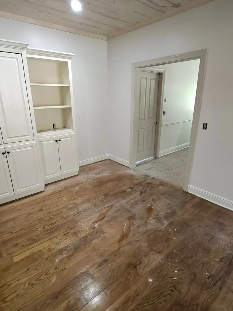 Empty room with white built-in shelves and freshly cleaned hardwood floors