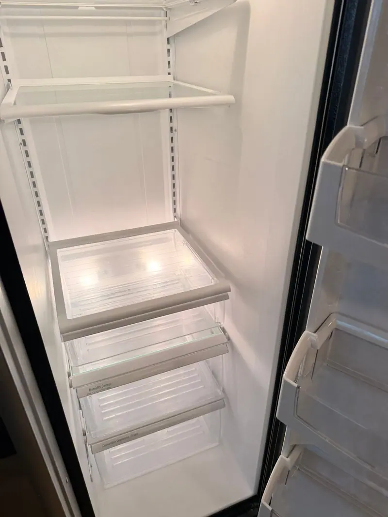 Inside of a refrigerator wiped clean, with clear glass shelves and empty door bins