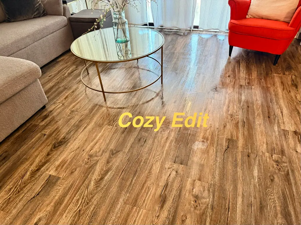 Living room with a glass coffee table, gray sectional and red armchair, the wood-look floor mopped to a shine