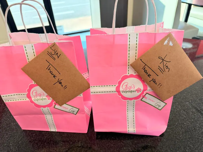 Pink thank-you gift bags with handwritten notes for two members of The Cozy Edit team