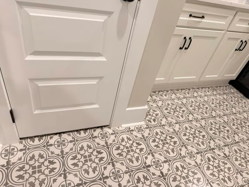 Patterned gray and white tile floor beside white cabinets, mopped clean