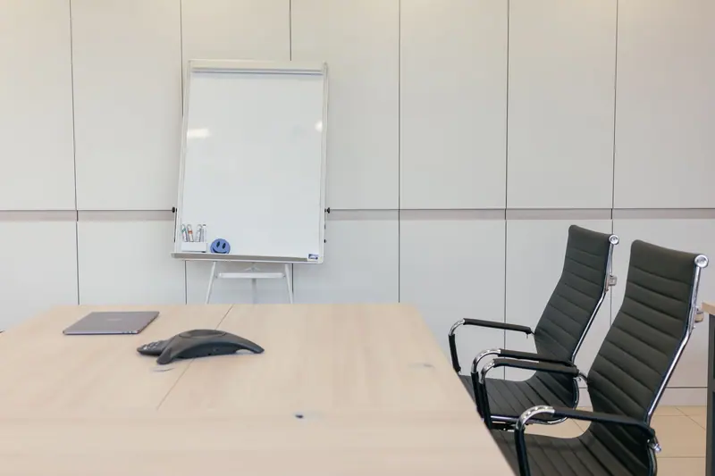 Clean conference room with a light wood table and whiteboard