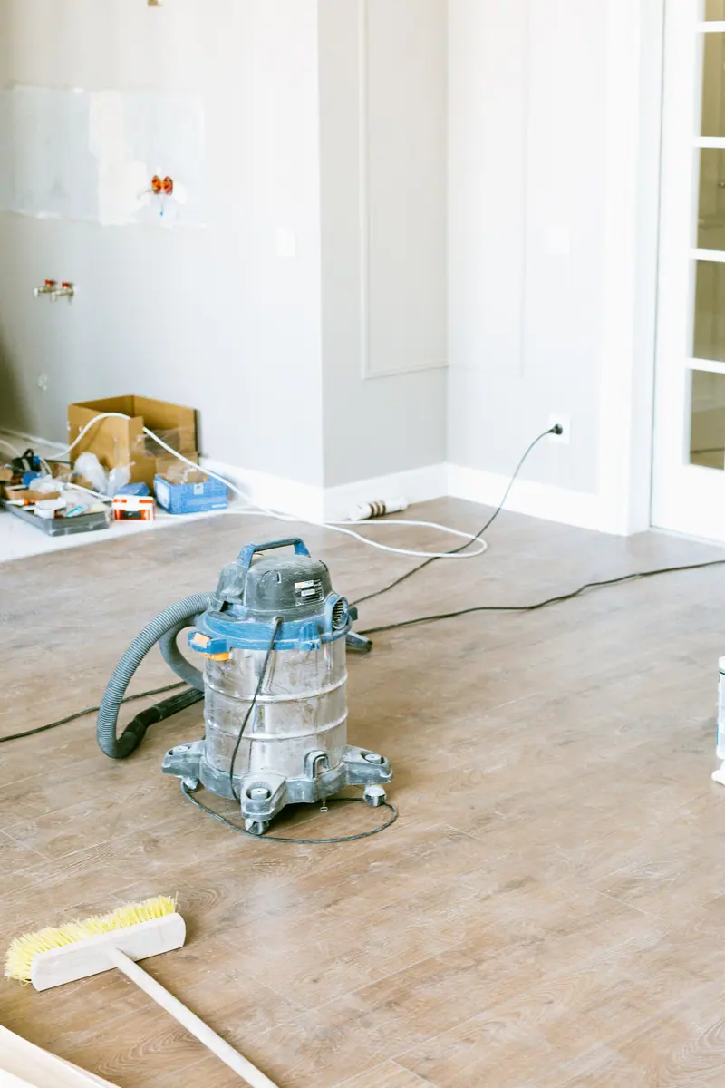 Shop vacuum and broom on a bare new floor after construction